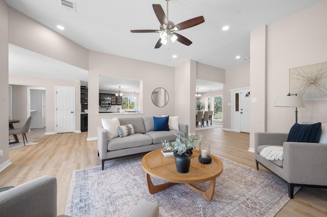 living room with visible vents, light wood-style flooring, ceiling fan with notable chandelier, recessed lighting, and baseboards