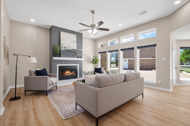 living area featuring light wood-style flooring, baseboards, visible vents, and a large fireplace