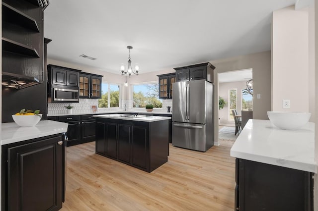 kitchen featuring glass insert cabinets, visible vents, a chandelier, and stainless steel appliances