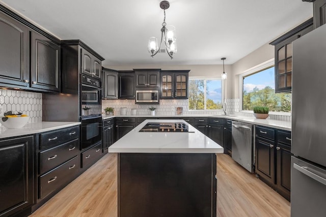 kitchen featuring glass insert cabinets, black appliances, light wood-type flooring, and light countertops