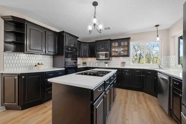 kitchen featuring light wood finished floors, visible vents, black appliances, and a sink