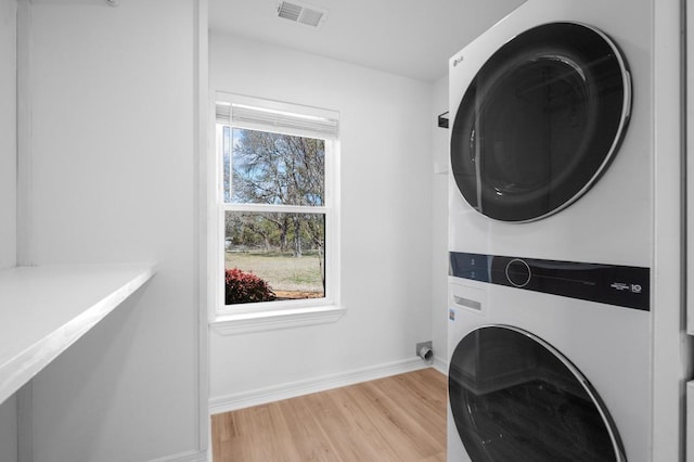 laundry room featuring visible vents, baseboards, laundry area, light wood-style flooring, and stacked washer / drying machine