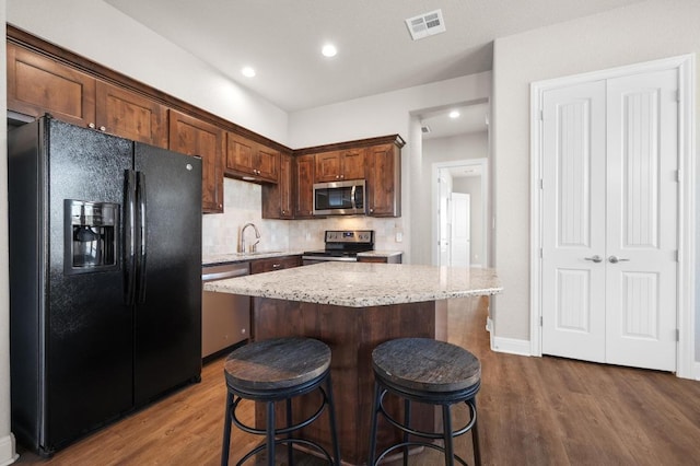 kitchen featuring dark wood-style floors, visible vents, appliances with stainless steel finishes, and a center island