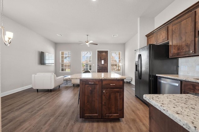 kitchen featuring open floor plan, dark wood finished floors, a center island, light stone countertops, and dishwasher