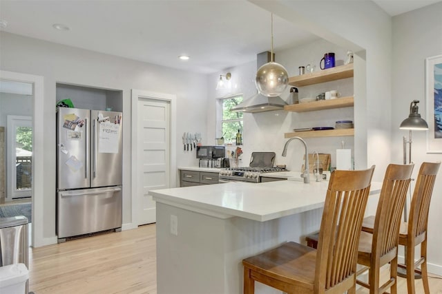 kitchen featuring ventilation hood, light countertops, light wood-style flooring, a peninsula, and stainless steel appliances