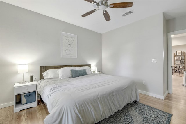 bedroom featuring a ceiling fan, visible vents, wood finished floors, and baseboards