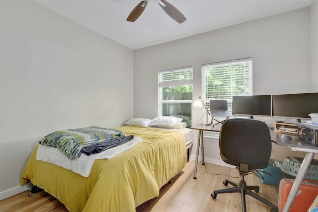 bedroom with a ceiling fan, wood finished floors, and baseboards