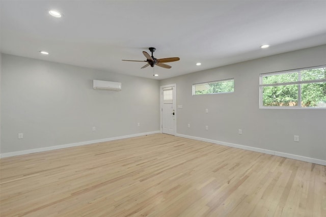 empty room with a ceiling fan, baseboards, recessed lighting, an AC wall unit, and light wood-style floors