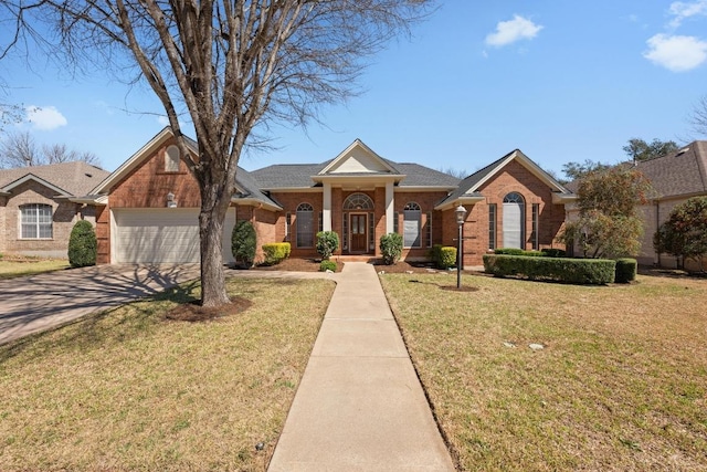 greek revival house featuring a front lawn, a garage, brick siding, and concrete driveway