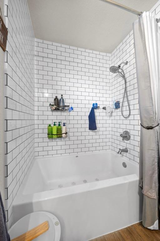 bathroom featuring wood finished floors and shower / bath combo with shower curtain