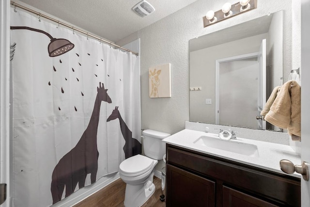 full bath with visible vents, toilet, a textured ceiling, wood finished floors, and vanity