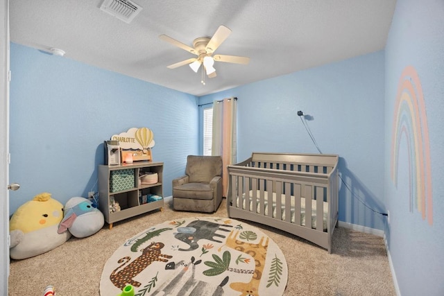 bedroom featuring visible vents, carpet floors, a nursery area, and a ceiling fan