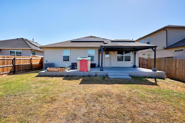 back of house featuring a patio, a fenced backyard, a gazebo, a yard, and solar panels