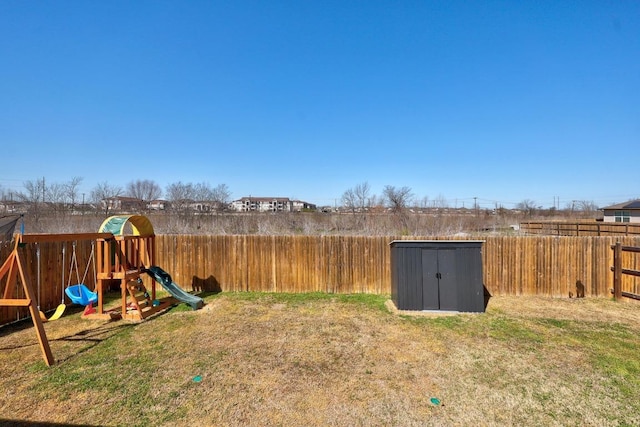 view of yard featuring a storage unit, an outdoor structure, a fenced backyard, and a playground