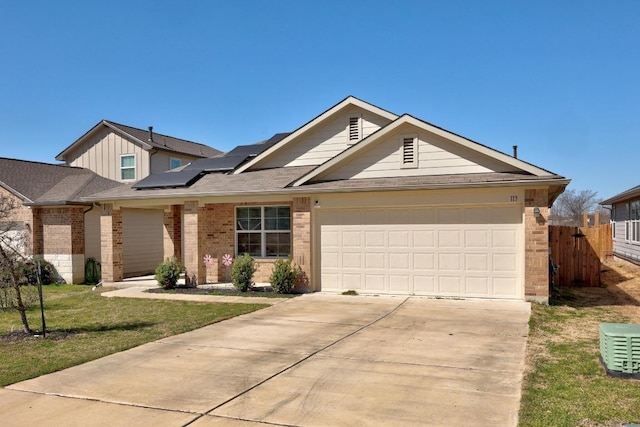 view of front facade with driveway, fence, a garage, brick siding, and solar panels