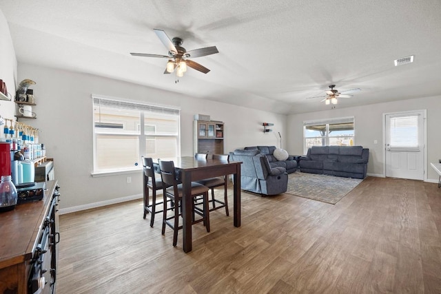 dining space with baseboards, wood finished floors, visible vents, and ceiling fan