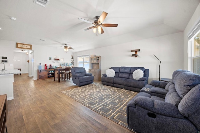 living area featuring a ceiling fan, wood finished floors, and visible vents