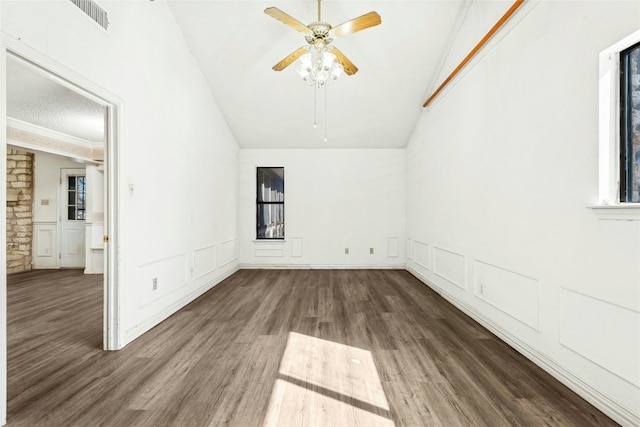 spare room with visible vents, wood finished floors, vaulted ceiling, and a decorative wall