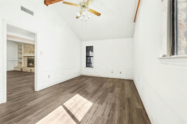 unfurnished room featuring visible vents, a large fireplace, a decorative wall, and wood finished floors