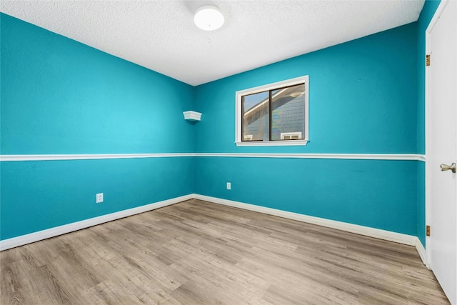 empty room featuring baseboards, a textured ceiling, and wood finished floors