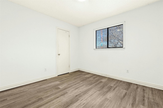 spare room featuring baseboards and wood finished floors