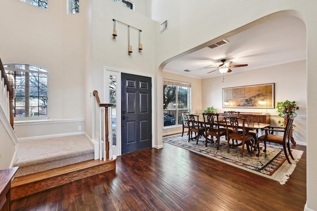 foyer with visible vents, arched walkways, wood finished floors, and stairway