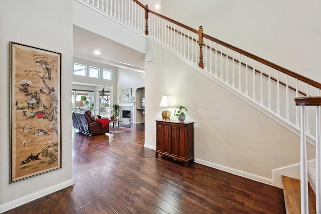 staircase with baseboards, a high ceiling, a fireplace, and hardwood / wood-style flooring