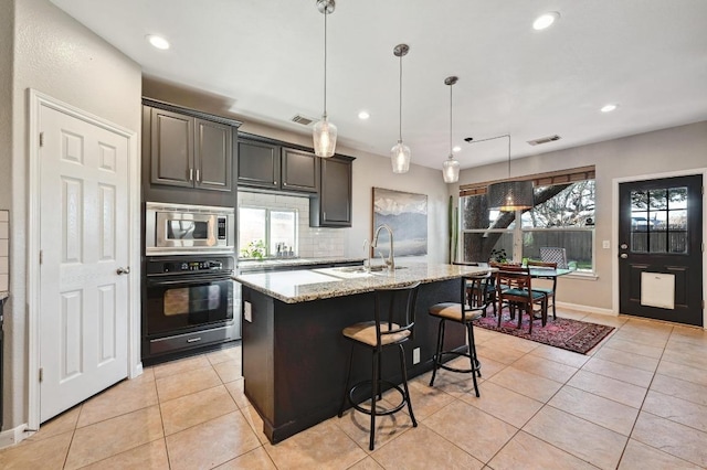 kitchen featuring oven, stainless steel microwave, visible vents, and light tile patterned floors