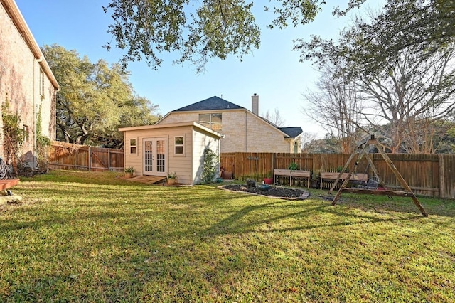 view of yard featuring french doors, an outbuilding, and a fenced backyard