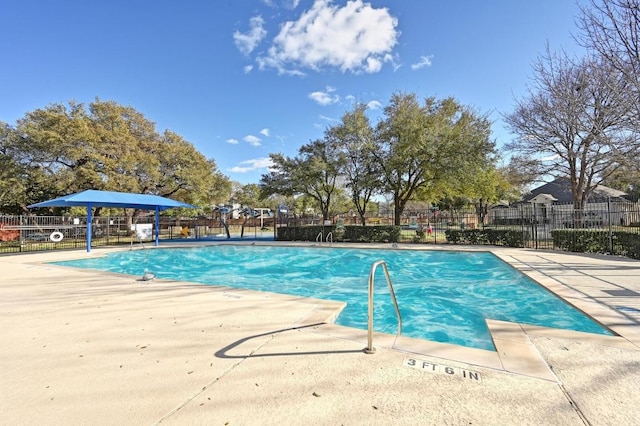 pool with a patio area and fence