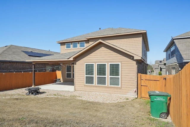 back of house featuring a patio, a fenced backyard, a lawn, and an outdoor fire pit