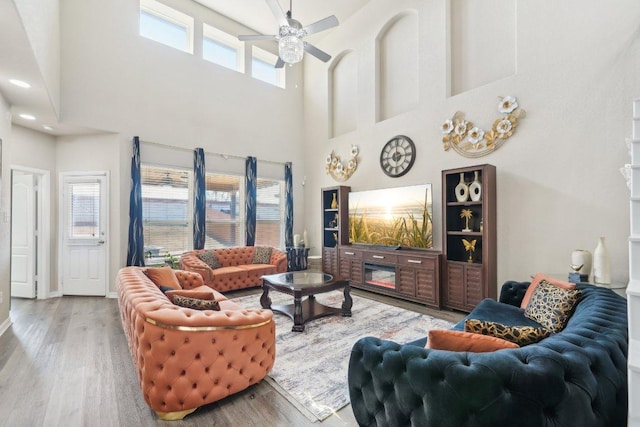 living area featuring ceiling fan, baseboards, and wood finished floors