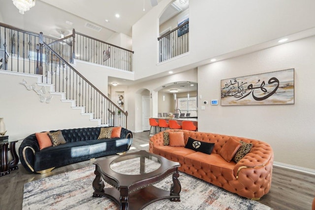 living room with stairs, visible vents, wood finished floors, and arched walkways