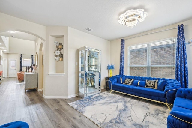 living room featuring wood finished floors, arched walkways, visible vents, and a healthy amount of sunlight