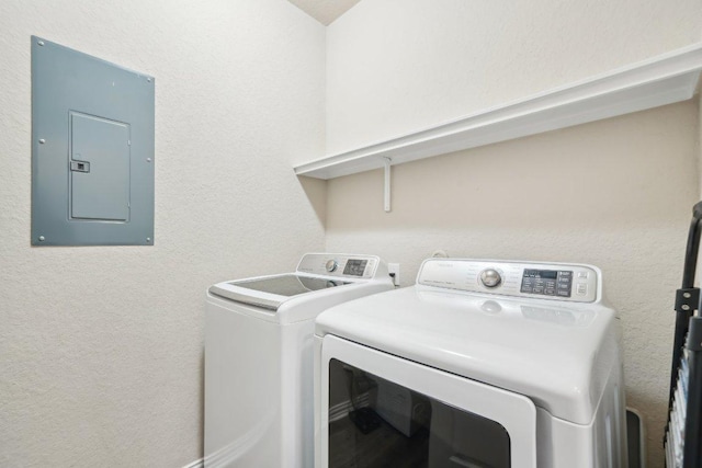 laundry area with electric panel, a textured wall, laundry area, and washing machine and clothes dryer