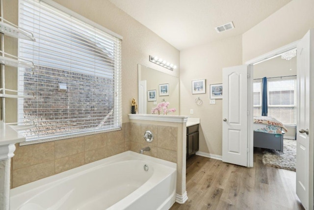 ensuite bathroom featuring visible vents, wood finished floors, connected bathroom, a bath, and vanity