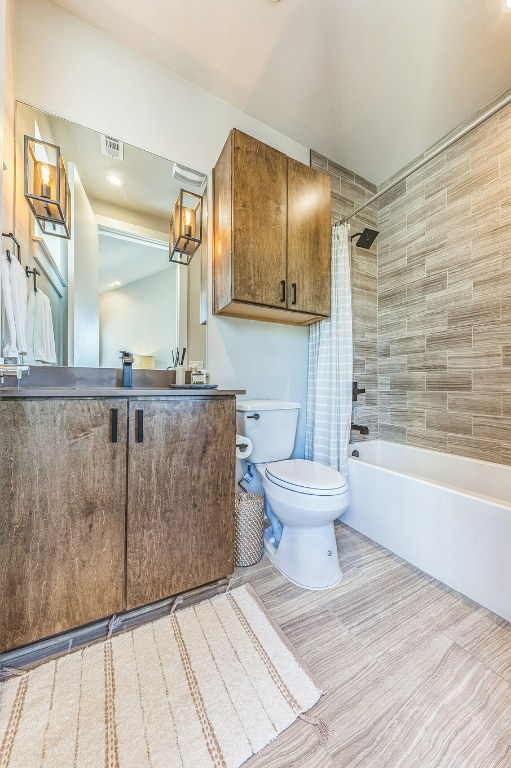 full bathroom with visible vents, shower / bathtub combination with curtain, toilet, and vanity