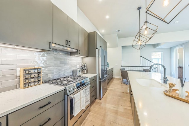 kitchen featuring visible vents, gray cabinetry, under cabinet range hood, appliances with stainless steel finishes, and a sink