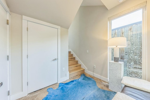 interior space featuring stairs, lofted ceiling, and baseboards