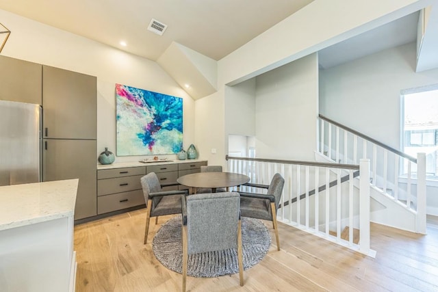 dining space featuring visible vents, light wood-style flooring, and stairway