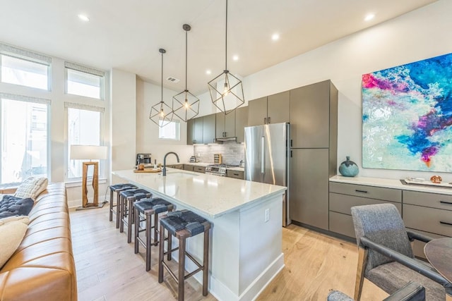 kitchen featuring a breakfast bar area, gray cabinetry, appliances with stainless steel finishes, and a sink