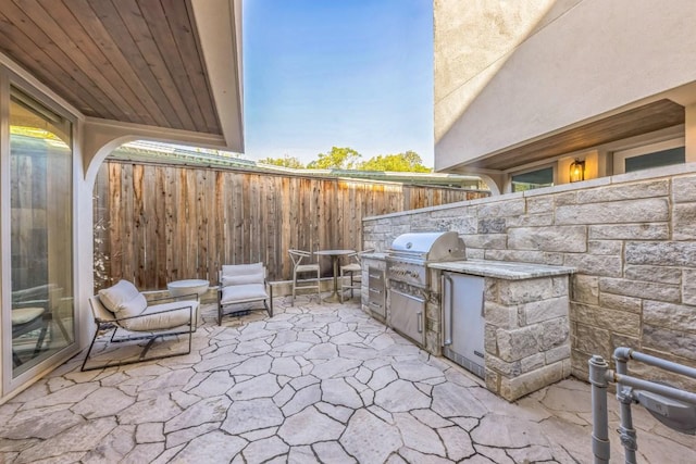 view of patio featuring area for grilling, exterior kitchen, and fence