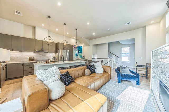 living area with visible vents, recessed lighting, stairs, and light wood-style floors