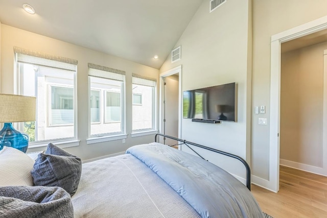 bedroom featuring visible vents, lofted ceiling, baseboards, and light wood finished floors