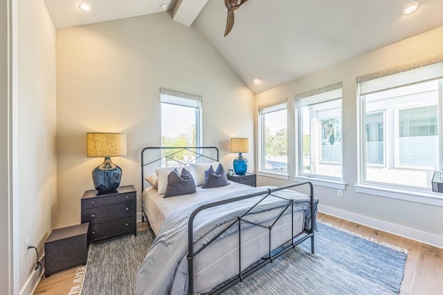 bedroom with beam ceiling, wood finished floors, baseboards, and high vaulted ceiling