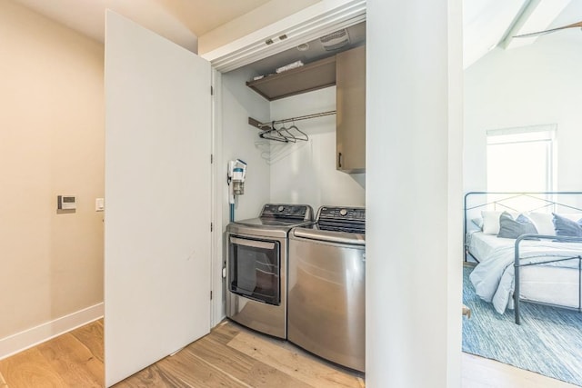 washroom with washer and clothes dryer, cabinet space, baseboards, and light wood-style floors