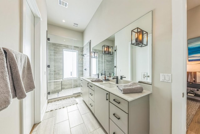 full bath featuring a sink, visible vents, a stall shower, and double vanity