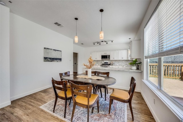 dining room featuring light wood-type flooring, visible vents, and baseboards