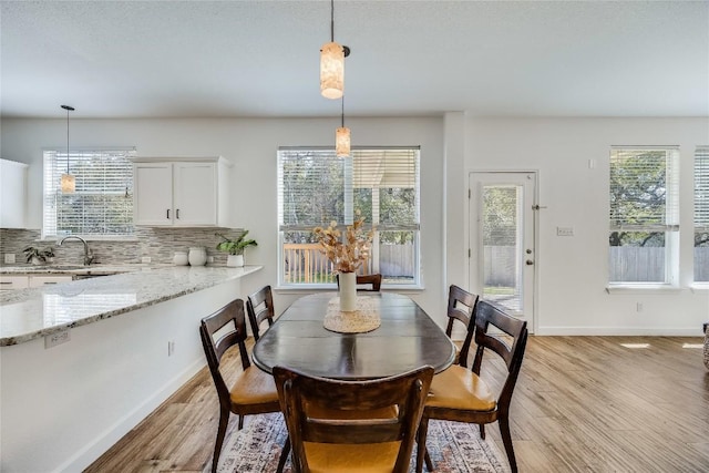 dining area with a wealth of natural light, baseboards, and light wood finished floors