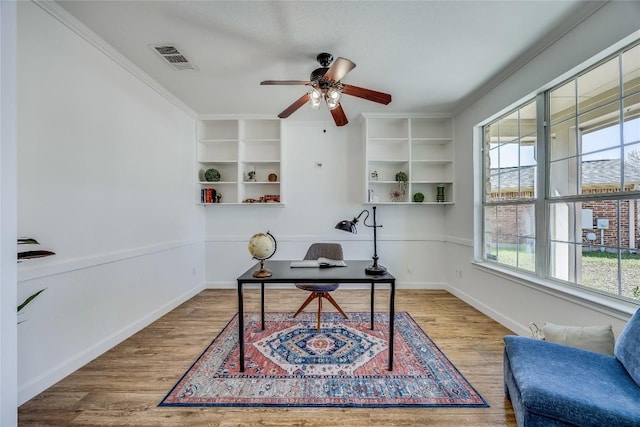 home office featuring visible vents, crown molding, ceiling fan, baseboards, and wood finished floors